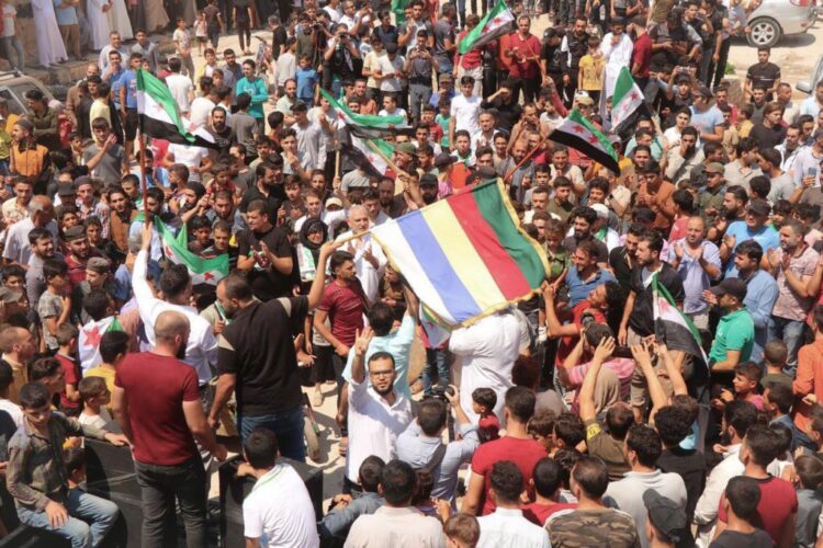 Protesters in Al-Bab, Aleppo province raise the Druze flag alongside the flag of the Syrian revolution in solidarity with Suwayda. (Source: Telegram)