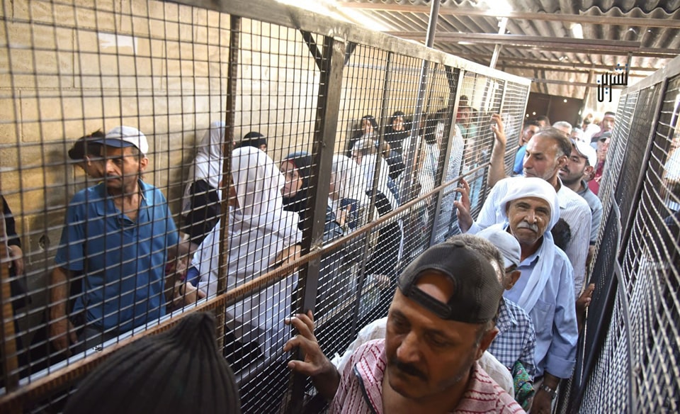 Syrians pictured in late July 2023 waiting in line for hours to receive their bread allotments from a Damascus bakery.